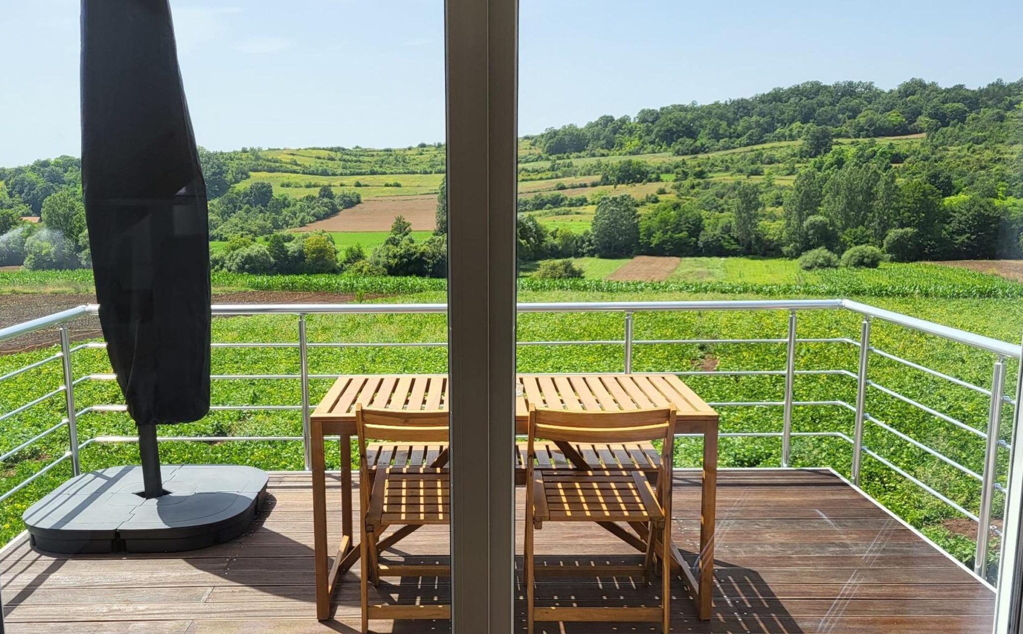 Pogled iz spavaće sobe Agro Lux apartmana na balkon i zelene predele, blizu Sokobanje i Vrmdže.